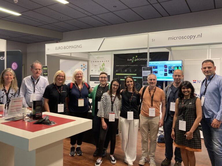 Conference picture featuring several attendees in front of an Euro-BioImaging promotional booth.